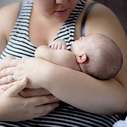 Woman in holding her infant, cradled in arms.