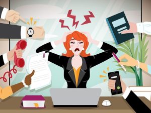 A stressed woman with red hair sits at a desk with a laptop, holding her head in both hands. Red zigzag lines above her head symbolize stress. Several hands surround her, each holding different items: a watch, a phone receiver, a piece of paper, an open book or folder, and a smartphone with an incoming call. One hand is pointing at her. On the desk are an open book and a computer mouse. The background features a potted plant and large office windows.