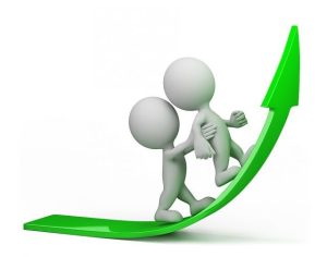 Two 3D humanoid figures are depicted on a green upward-curving arrow. One figure is helping the other climb up the arrow, symbolizing support or teamwork in achieving growth or progress.