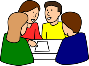 Four individuals seated around a table in discussion, with one person pointing at a document, suggesting collaborative decision-making or planning.